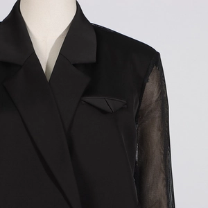 Détail du blazer noir élégant avec manches en résille transparente et revers en pointe sur mannequin
