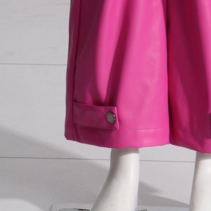 Dettaglio dei pantaloni in pelle rosa fenicottero con cinturino e fibbia in metallo argento