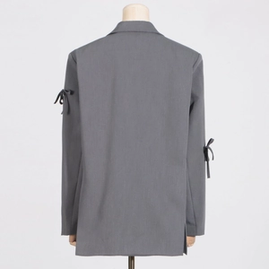 Vue détaillée d'un blazer gris foncé montrant des nœuds sur les manches et la texture