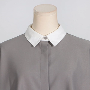 Close-up of minimalist grey top featuring contrast white collar and hidden button detail