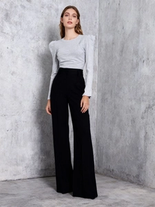 Detail view of stylish puff sleeve top and high-waist trousers on minimalist grey background