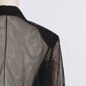 Détail de blazer en tulle noir montrant le tissu transparent et la couture du col