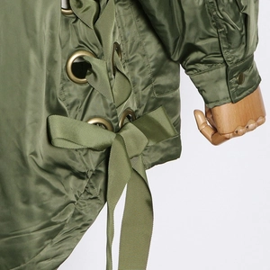 Close-up of army green jacket side laces with gold metal eyelets and textured straps