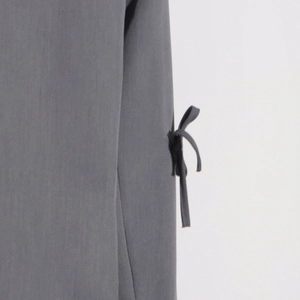Détail de la veste de costume gris foncé montrant la sangle latérale et le nœud papillon