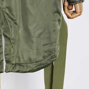 Detail of army green parka fabric with precise stitching and matching woven belt