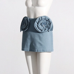 Detail van lichtblauwe denim minirok met grote 3D-spiraalvormige bloemen van stof