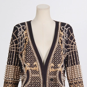Détail du cardigan noir avec motifs dorés et embellissements de perles blanches