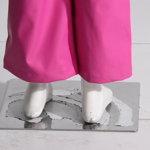 Dettaglio dei pantaloni a gamba larga in ecopelle rosa acceso con cuciture sull'orlo