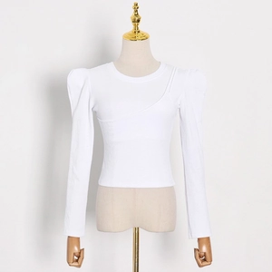 Detail of white ribbed knit tee featuring puff shoulders and asymmetrical seam design