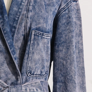 Detailansicht der säuregewaschenen Denim-Textur und des Taillengürtels an der Jacke