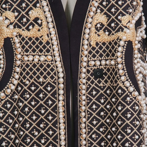 Détail de manteau luxueux avec imprimés dorés, col en V et finitions en perles