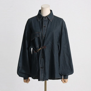 Dettaglio della giacca di jeans blu scuro con un'elegante fibbia metallica in vita