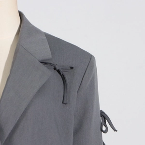 Détail d'un blazer gris avec des nœuds coulissants tendance sur l'épaule et la manche