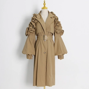Detailed close-up of khaki trench coat featuring layered ruffle shoulders and retro lantern sleeves