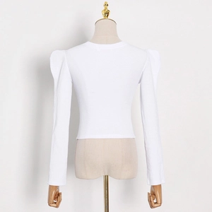 Detail view of white ribbed knit fabric and puff sleeve shoulder construction on slim top
