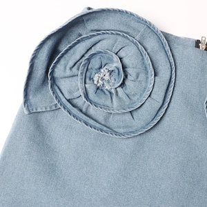 Detail van blauwe denim minirok met handgemaakte 3D-roos en metalen ritssluiting