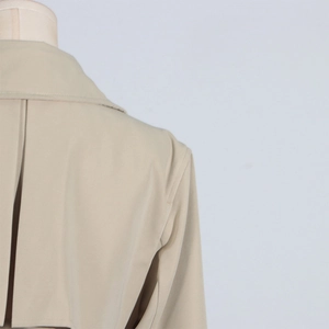 Detailed view of the back gun flap and stitching on this beige trench coat for women