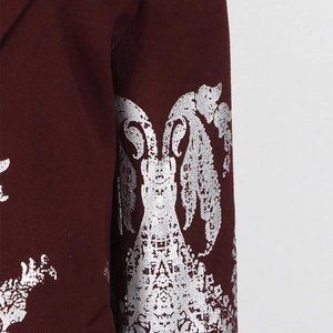 Détail macro du tissu blazer rouge vin avec des imprimés floraux vintage argentés