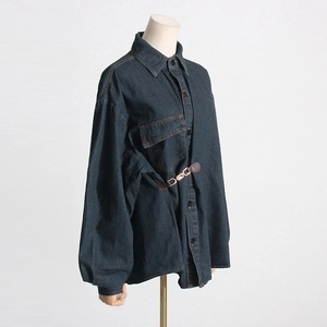 Dettaglio della giacca in denim blu scuro con cintura a morsetto e tasca sul petto