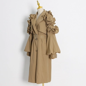 Detail view of khaki trench coat featuring tiered ruffle shoulders and adjustable lantern sleeves