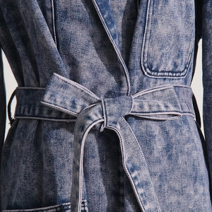 Detailansicht der Taillenschleife und der hochwertigen Twill-Textur des Denim-Mantels