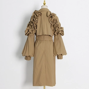 Detail view of khaki trench coat featuring dramatic pleated ruffles and puffed sleeves