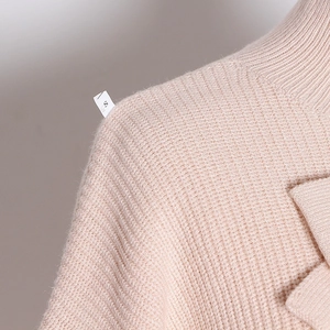 Detail shot of pink knit sweater featuring waffle texture and shoulder size S tag