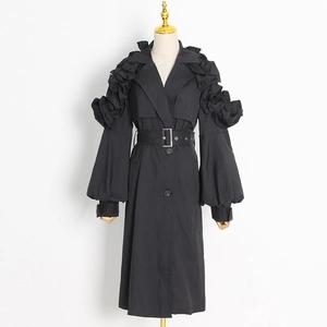 Detailed view of ruffle tiered lantern sleeves and silver buckle belt on black trench coat