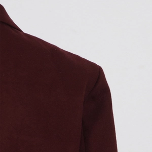 Gros plan de l'épaule d'un costume en laine bordeaux montrant la texture du tissu