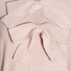 Close-up of pink knit top detailing refined stitching and large decorative bow design