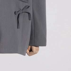 Détail d'une veste de costume gris foncé avec nœud latéral et texture de tissu fine