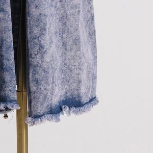 Detailansicht eines hellblauen Denim-Mantels mit Fransensaum und starker Waschung