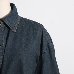 Dettaglio giacca in denim blu scuro con cuciture arancioni a contrasto e colletto