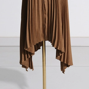 Macro view of coffee brown pleated skirt featuring irregular hemline and fine fabric texture