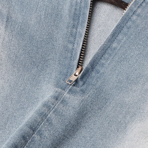 Detailopname van de metalen rits op een lichtblauwe denim rok met stonewashed effect