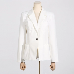 Détail de blazer blanc montrant des poches à rivets métalliques et une coupe cintrée femme