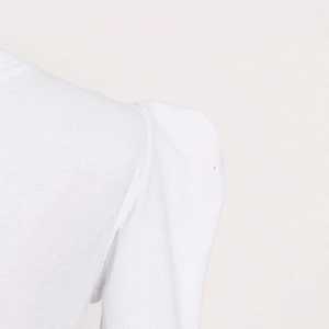 Macro detail of white ribbed knit fabric featuring puff shoulder design and pleat texture