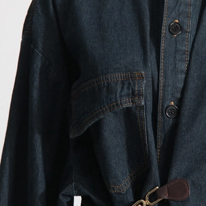 Dettaglio della giacca di jeans blu scuro con cuciture arancioni e tasca a pattina