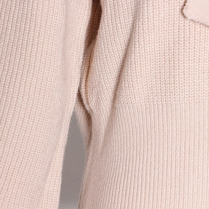 Macro shot of apricot knit sweater showing detailed rib and honeycomb texture stitching