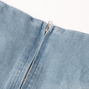 Detail van de denim stoftextuur en de zilveren metalen ritssluiting van de korte rok