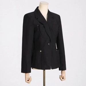 Détail d'un blazer noir ajusté pour femme avec rivets métalliques et fermeture à bouton unique