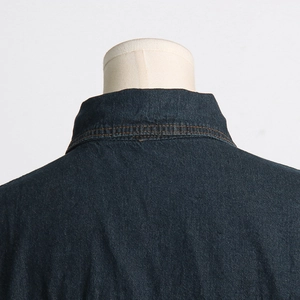 Dettaglio del colletto di una giacca di jeans blu scuro con cuciture precise e trama