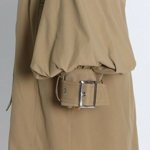 Close-up of khaki trench coat cuff with adjustable silver buckle and puff sleeve detail