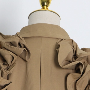 Detailed close-up of ruffles on the shoulder and back pleats of the khaki trench coat