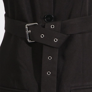Detail of a black dress with high-waist belt featuring a silver metal square buckle and eyelets