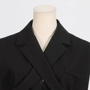 Detail of black sleeveless blazer showing the unique crisscross lapel and clean tailoring