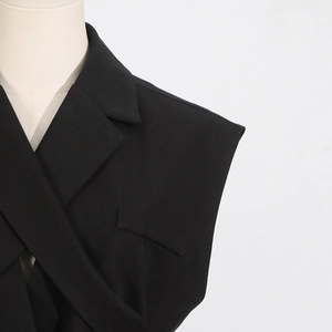 Detailed close-up of a black sleeveless blazer with notched lapels and textured fabric