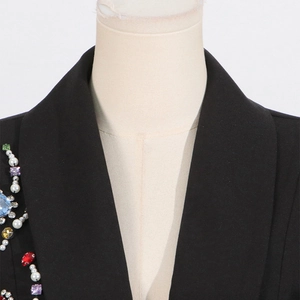 Detail of lapel featuring colorful rhinestones, pearls, and red heart gems on a black blazer