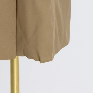 Close-up of khaki trench coat hem showing high-quality twill fabric and neat stitching
