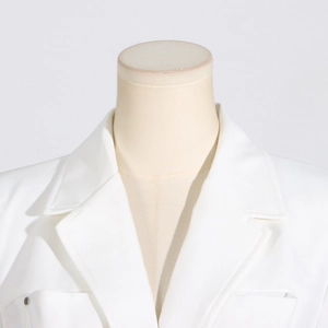 Gros plan détaillé du revers du blazer blanc montrant les coutures et le tissu texturé